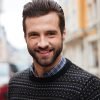 Close up portrait of a young smiling man looking at camera outdoors